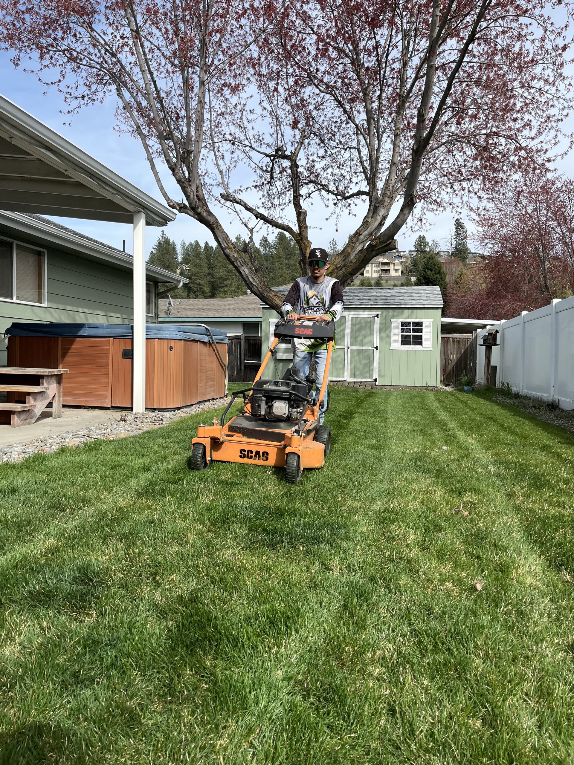 IMG_9027 A Spokane's Finest Lawns employee edging a sidewalk during a mowing service. There is a Spokane's Finest Lawns truck behind him.